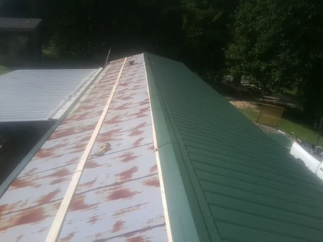 Old rusted panels beside newly installed green metal roofing — Wind Damage Roof Repair by Roofing Brothers in Larned