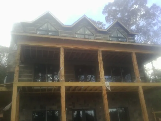 Dormers and porch framing on a large log home under construction — Roof Coating work by our crew in Larned
