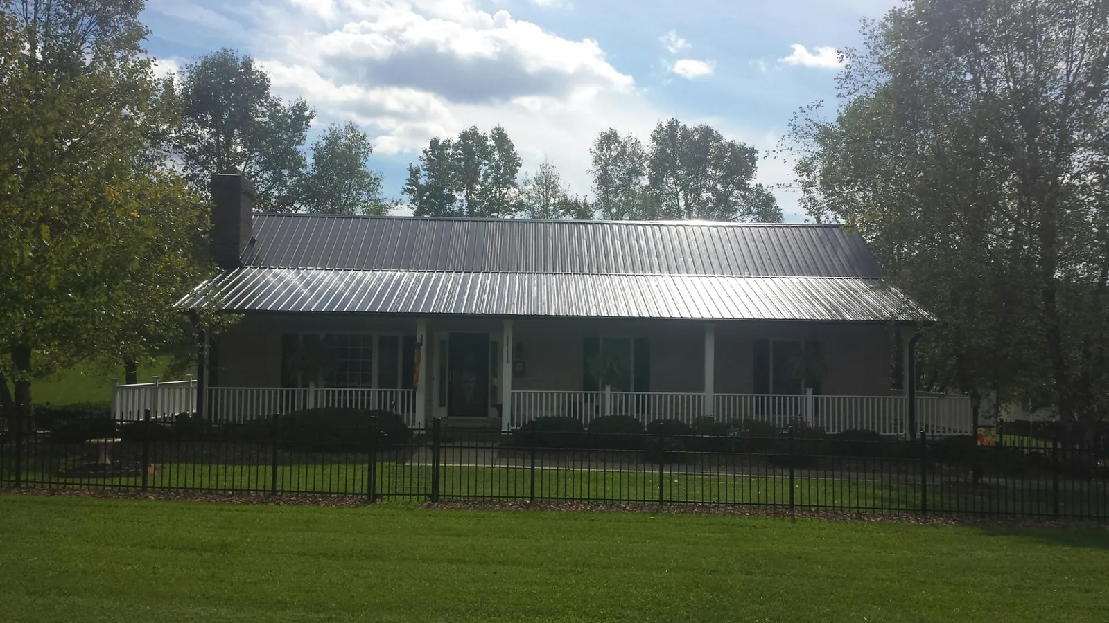 Gray metal roof on a brick ranch with a full width front porch — Gutter Guard Installation work by our crew in Larned