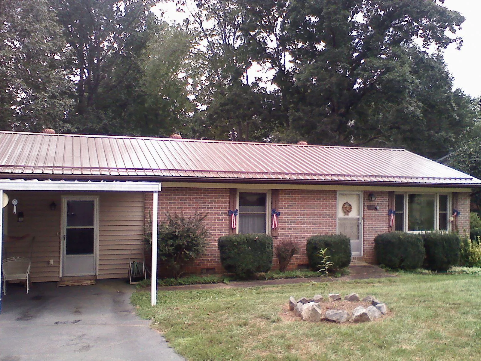 Bronze metal roof and carport on a brick ranch home — Roof Repair work by our crew in Larned
