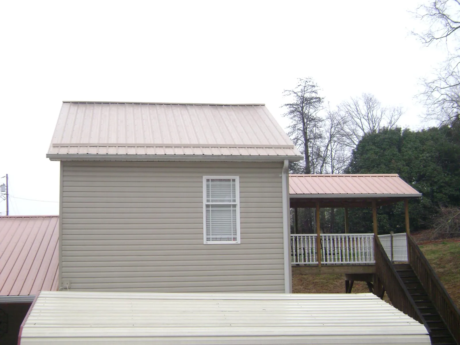 Tan metal roofs on a two story addition and attached porch, from a Roof Replacement job in Larned