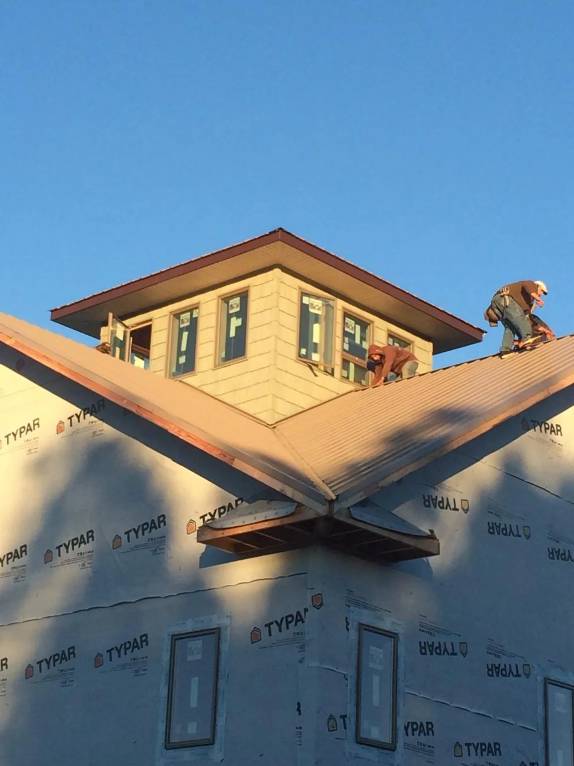 Roofers working around a rooftop cupola on a new metal roof at sunset — Roof Waterproofing in Larned by Roofing Brothers